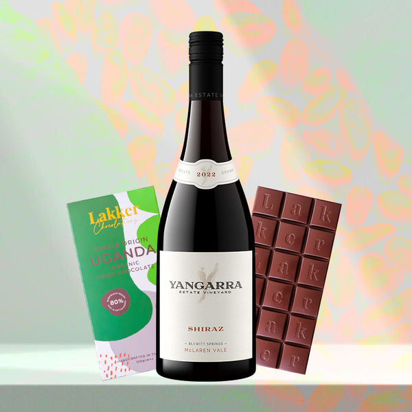 Gift arrangement displaying a bottle of red wine, a box of single-origin Ugandan organic chocolate, and a segmented dark chocolate ba
